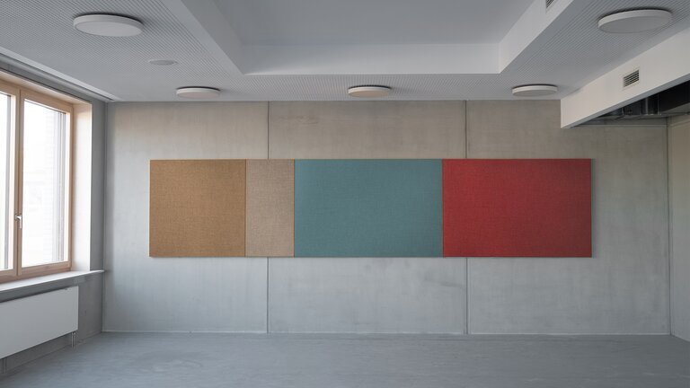 Vier bunte Wandpaneele in leerem Raum.